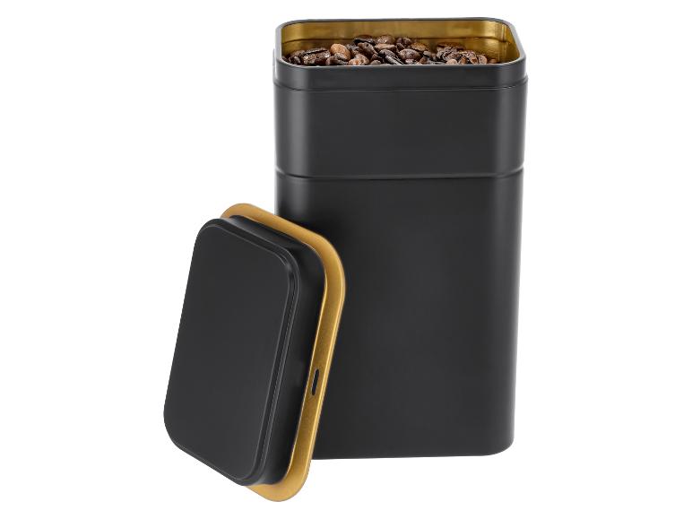 Zwart metalen koffieblik met gouden binnenkant en deksel, gevuld met koffiebonen.