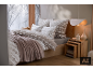 Gezellig bed met beddengoed met Noors patroon en een zachte deken in een winterslaapkamer.