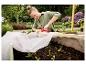 Vrouw bevestigt vliesdoek met Rapid R53 tacker op een moestuinbak met plantjes.