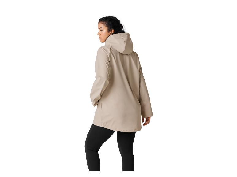 Vrouw in beige regenjas met capuchon en zwarte legging, met de rug naar de kijker