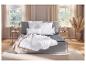 Grijs boxspringbed met wit beddengoed en sprei in een slaapkamer met raam.