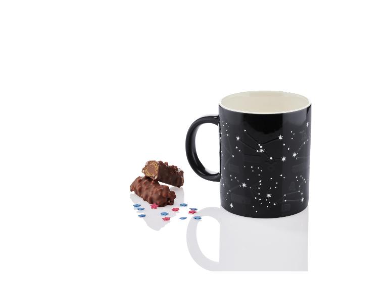 Een zwarte mok met sterrenbeeldprint en twee chocolade-repen.