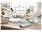 Wit porseleinen servies op een rustieke houten tafel, met fruit en bloemen.