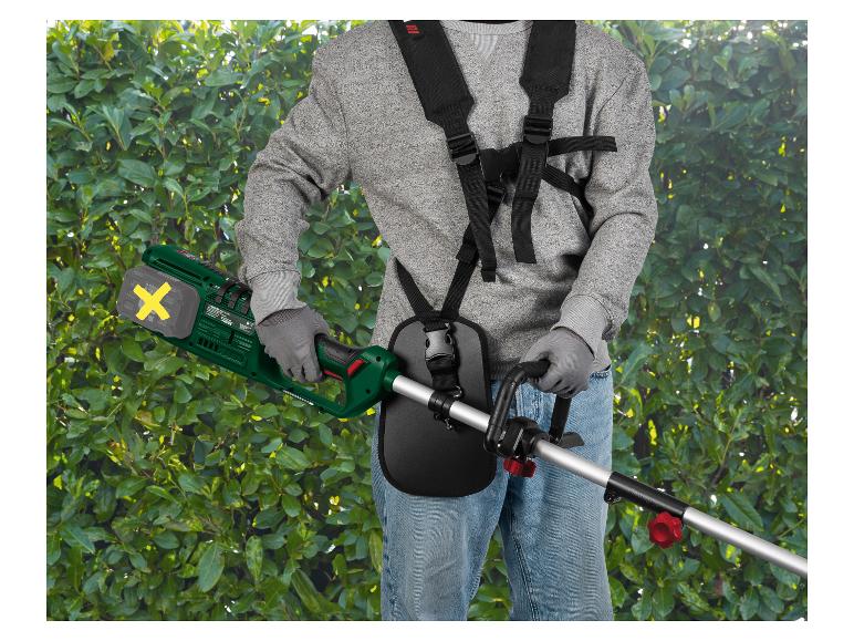 Man met accubosmaaier en harnas, snoeit een groene struik.