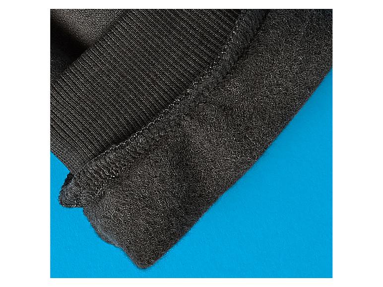 Close-up van zwarte thermische stof met geribbelde rand op blauwe achtergrond.