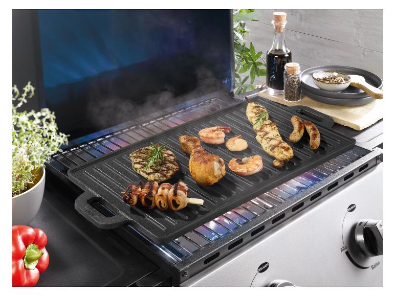 Grillplaat met diverse vleessoorten en zeevruchten, waaronder kip, garnalen en worsten.