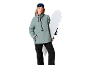 Vrouw in groene ski-jas en zwarte skibroek met snowboard en skibril.