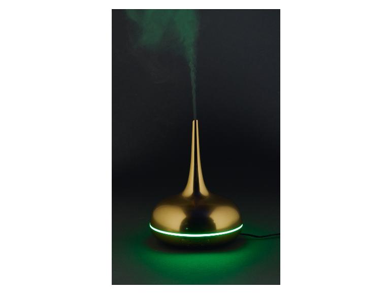 Gouden aroma diffuser met groen licht en rook op een donkere achtergrond