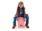 Een lachende jongen zit op een roze XDRUM cajon en slaat erop met zijn handen.