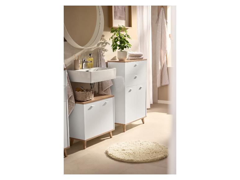 Badkamer met witte kasten, houten bladen, wastafel en ronde spiegel.