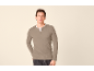Man draagt een grijsbeige Henley-shirt met lange mouwen en een donkere spijkerbroek.