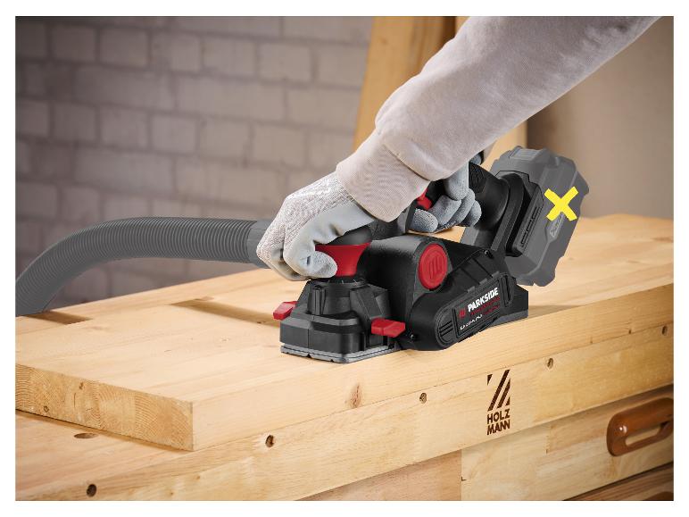 Een persoon gebruikt een elektrische schaaf op een houten plank, met een aangesloten afzuigslang.