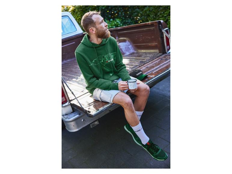 Man in groene Parkside hoodie zit op de laadbak van een pick-up truck.