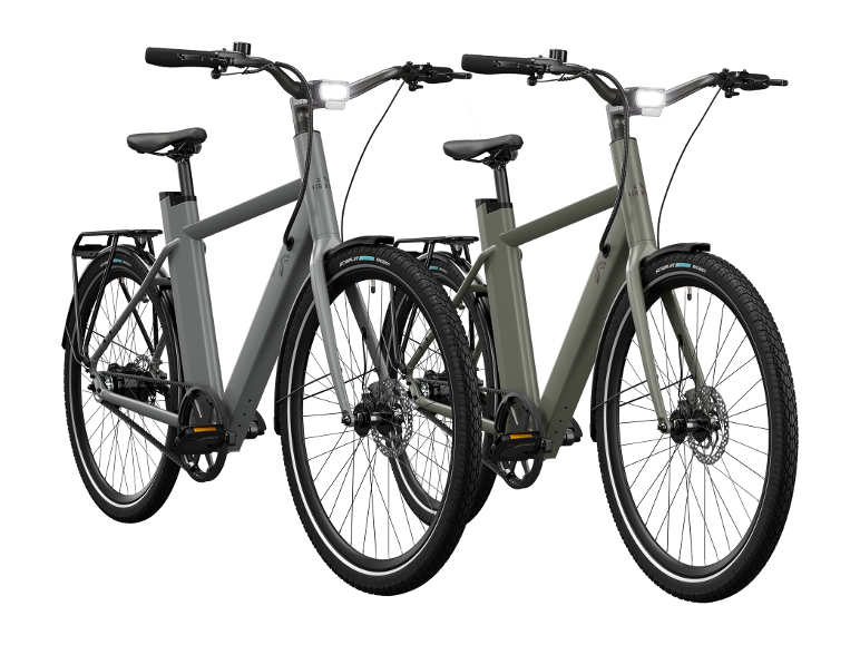 Twee moderne elektrische fietsen, één grijs en één olijfgroen, met geïntegreerde verlichting.