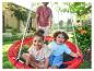 Twee lachende kinderen in een rode tuinschommel, met vader op de achtergrond.