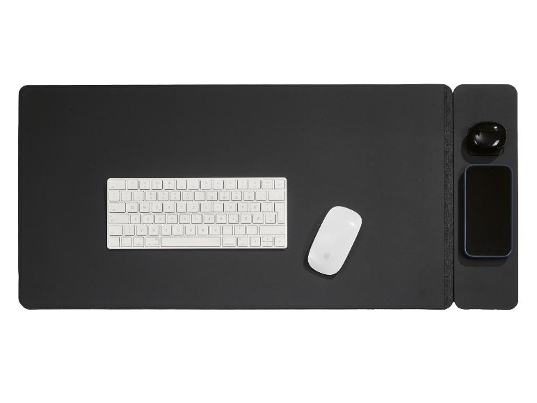 Toetsenbord, muis, oordopjes en smartphone op een zwarte bureauonderlegger.