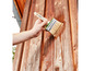 Houten wand wordt geverfd met een penseel.