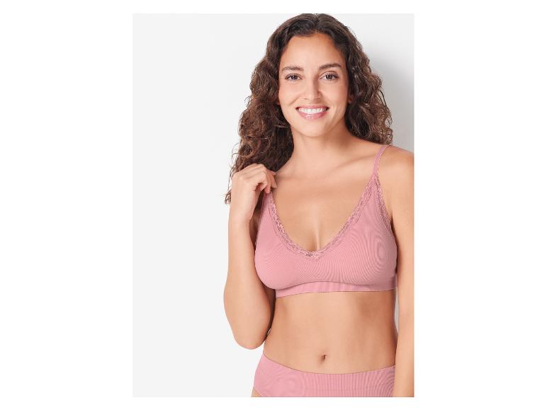 Een vrouw draagt een roze bralette met kanten details.