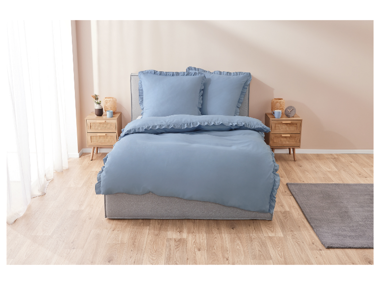 Lichtblauwe beddengoed met ruches op een bed in een gezellige slaapkamer.