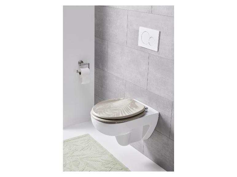 Een toilet met een beige toiletbril met palmbladerenpatroon.