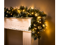 Kerstslinger met warmwitte LED-lampjes op een witte schouw.