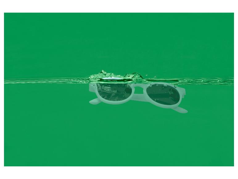 Witte zonnebril drijft in groen water met spetters.
