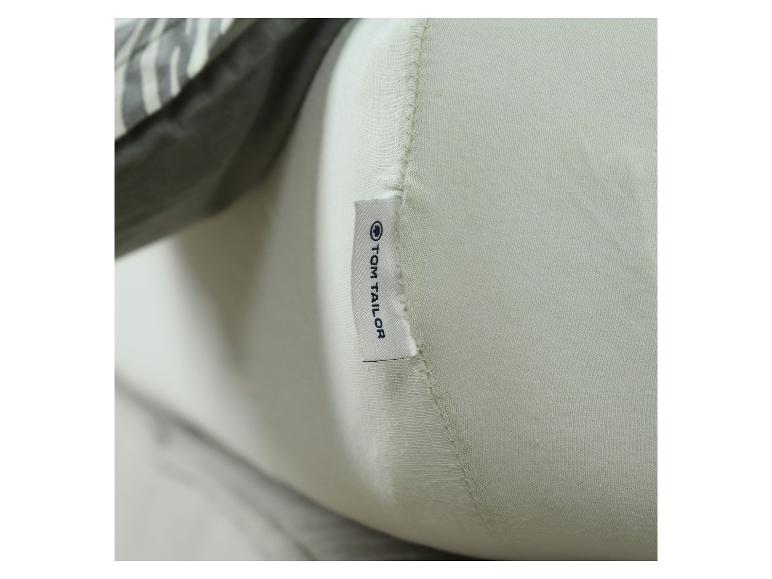 Lichtgroen kussen met een label met „TOM TAILOR” en een patroonstof op de achtergrond.