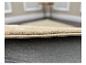 Close-up van de rand van een beige pluche tapijt met een antislip onderkant.