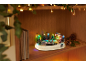 Kerstdecoratie met schaatsbaan, kerstbomen en lichtjes op een houten plank.