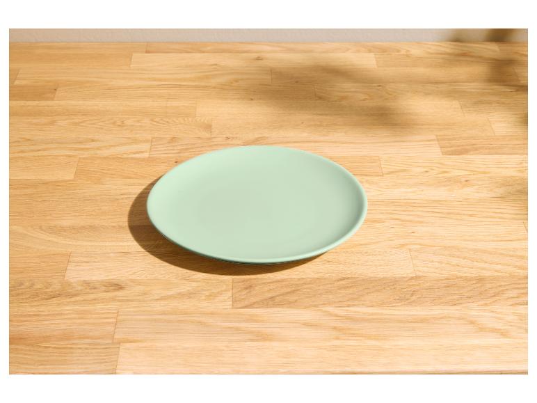 Lichtgroen bord op een lichte houten tafel met schaduwen