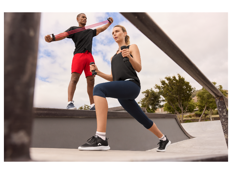 Een man en een vrouw trainen met dumbbells en weerstandsbanden buiten.
