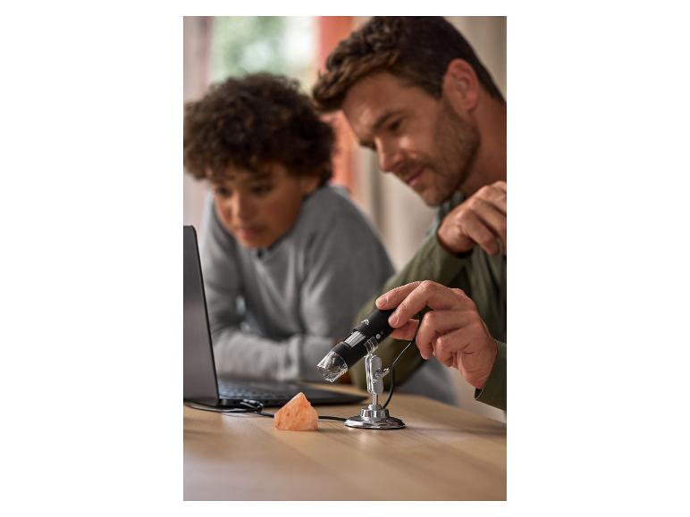 Vader en zoon gebruiken een digitale microscoop om een roze steen te onderzoeken.