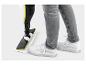Persoon maakt vloer schoon met stoommop, draagt grijze jeans en witte sneakers.