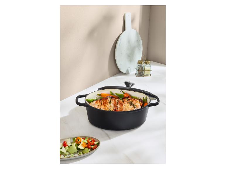 Zwarte braadpan met gebraden vlees en groenten, met een salade ernaast.