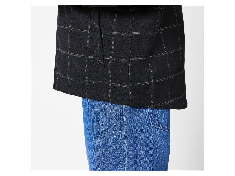 Een donkergrijze geruite blazer over een blauwe jeans.