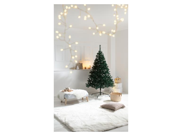 Ongedecoreerde groene kerstboom in een woonkamer met feestelijke decoraties.