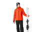 Man in oranje ski-jas en zwarte skibroek met ski's.