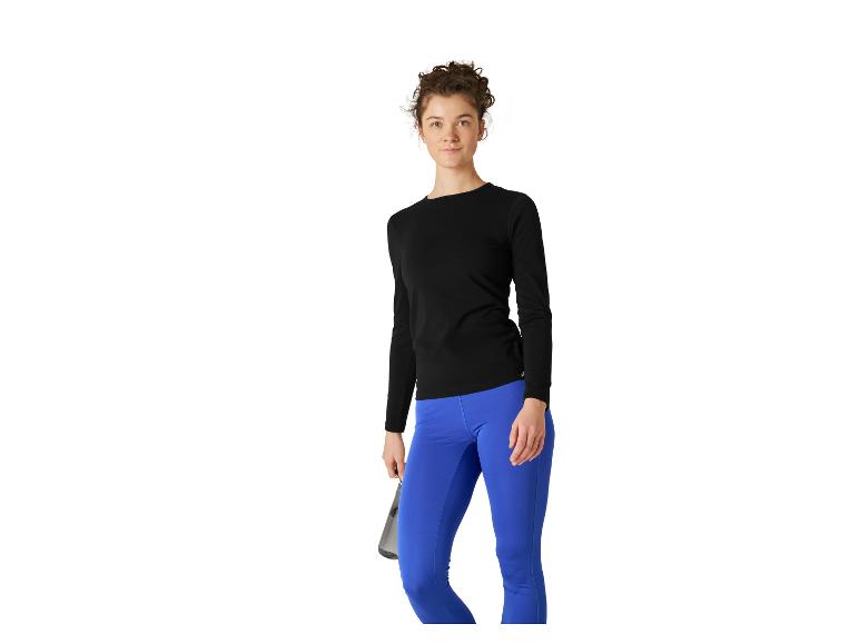 Vrouw in zwart shirt met lange mouwen en blauwe legging, met waterfles.