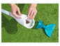 Een witte zwembadstofzuiger met een blauwe schep op gras.