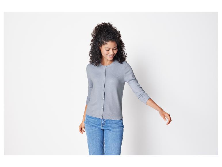 Een vrouw draagt een grijs vest en blauwe jeans.