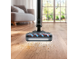 Stofzuiger reinigt houten vloer met vuil en haar in een woonkamer.