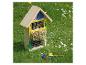 Houten insectenhotel met kleurrijke details in een grasveld met madeliefjes.