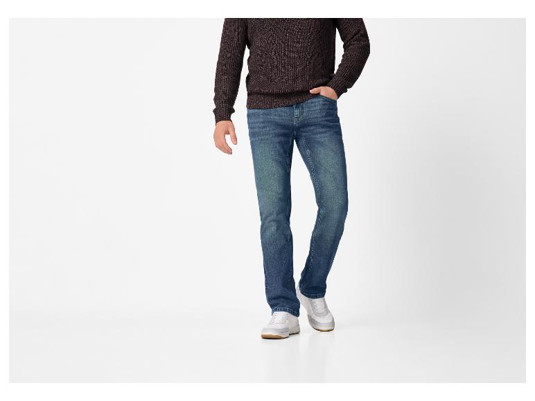 Man in bruine gebreide trui, blauwe jeans en witte sneakers