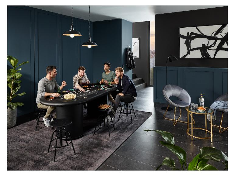 Vier mannen pokeren aan een zwarte pokertafel met hoge stoelen.