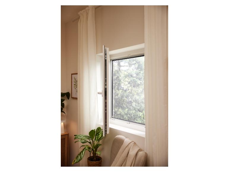 Open raam met hor, gordijnen, kamerplant en fauteuil.