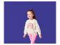 Meisje in crèmekleurige sweatshirt met regenboogprint en roze legging.