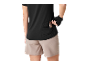 Vrouw in zwart sporttopje en beige shorts, stopt een snackreep in een achterzak.