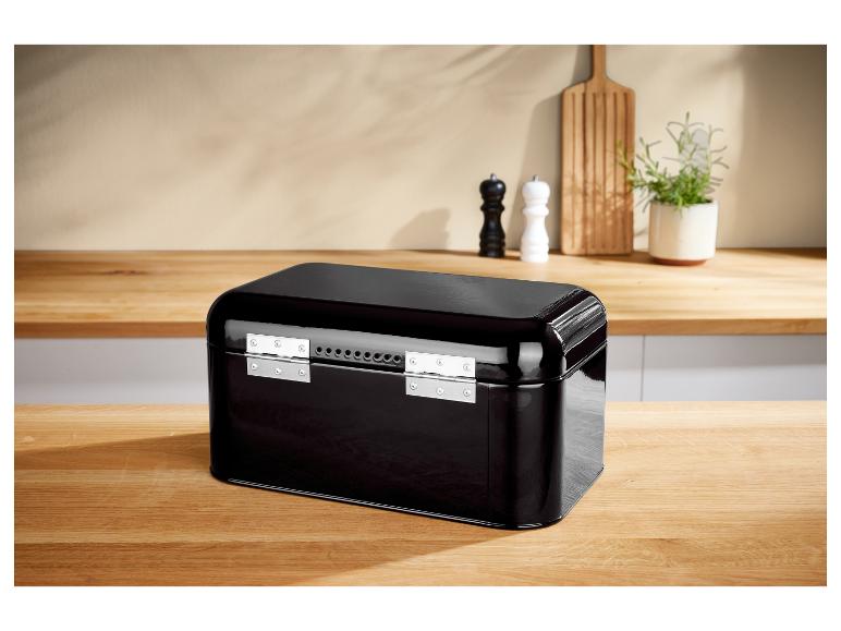 Zwarte metalen broodtrommel op een houten aanrecht in een keuken.