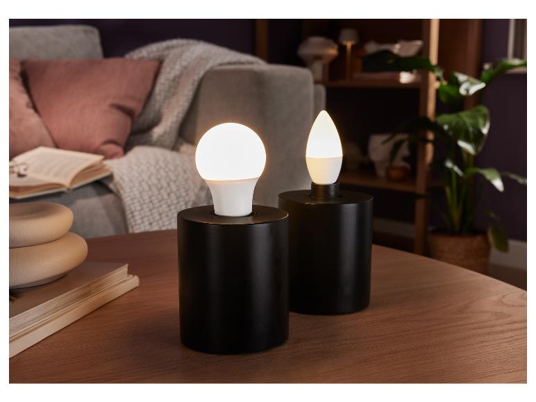Twee zwarte lampen met ronde en druppelvormige LED-lampen op een houten tafel.