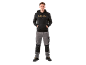 Man in zwarte hoodie en grijze werkbroek, met handen in de zakken.